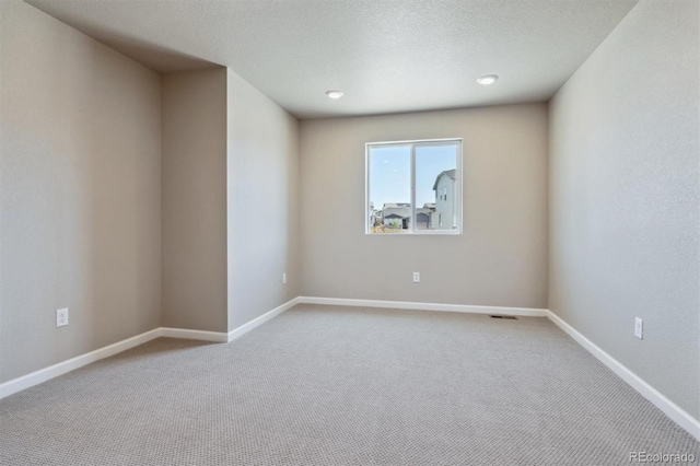 carpeted empty room featuring a textured ceiling