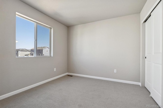 unfurnished bedroom with light colored carpet and a closet