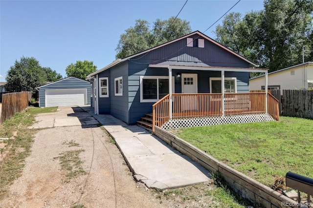 bungalow-style house featuring a garage, a porch, a front yard, and an outbuilding