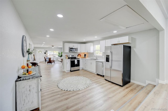 kitchen with light wood-type flooring, sink, stainless steel appliances, and white cabinets