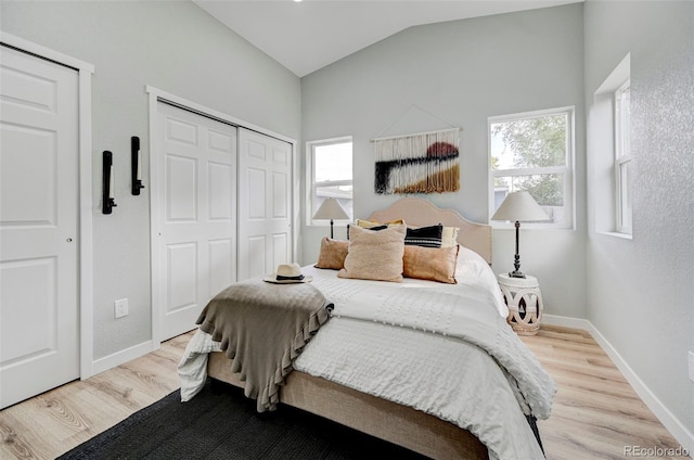 bedroom featuring light wood-type flooring, vaulted ceiling, and multiple windows