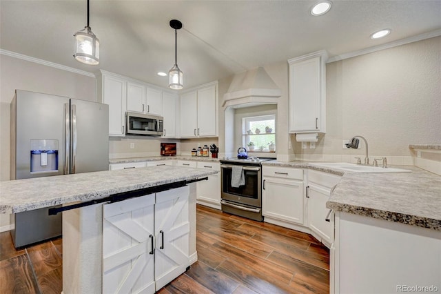 kitchen featuring stainless steel appliances, a sink, recessed lighting, crown molding, and white cabinetry