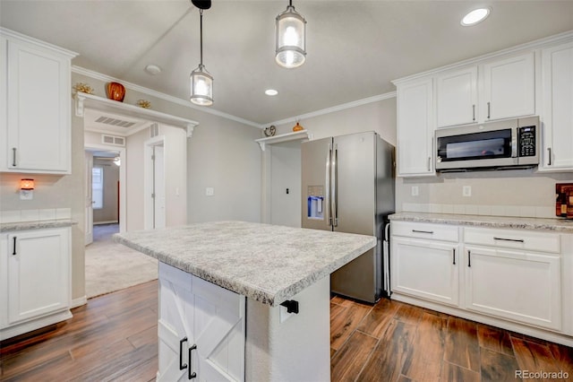 kitchen with appliances with stainless steel finishes, dark wood finished floors, crown molding, white cabinets, and pendant lighting