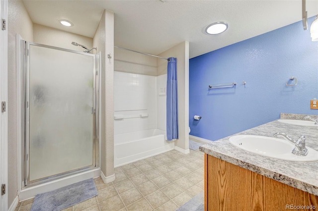 full bath featuring baseboards, double vanity, tile patterned flooring, a textured ceiling, and a textured wall