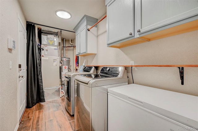 laundry room featuring cabinet space, washer and dryer, light wood finished floors, baseboards, and gas water heater