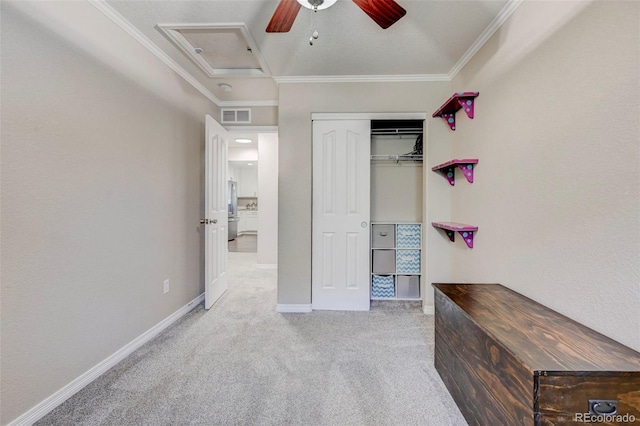 unfurnished bedroom featuring carpet flooring, ornamental molding, attic access, baseboards, and a closet