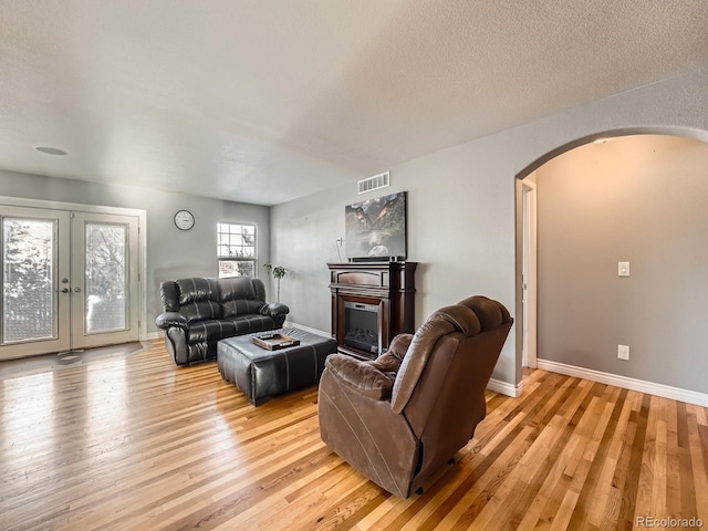 living room featuring french doors, light hardwood / wood-style floors, and a textured ceiling