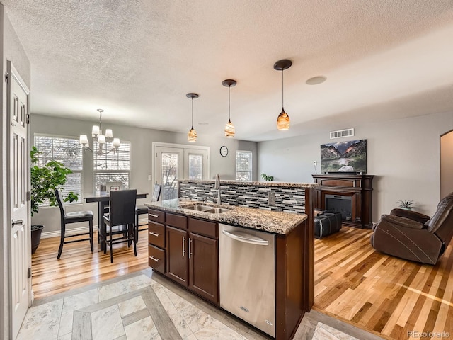 kitchen with dishwasher, sink, light stone counters, decorative light fixtures, and decorative backsplash