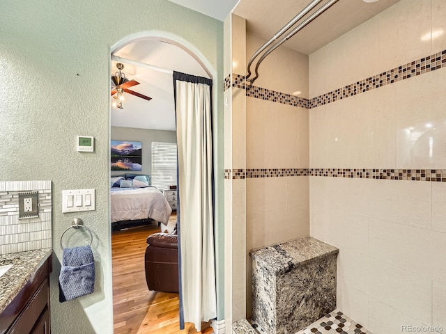 bathroom featuring a tile shower, ceiling fan, hardwood / wood-style floors, and vanity