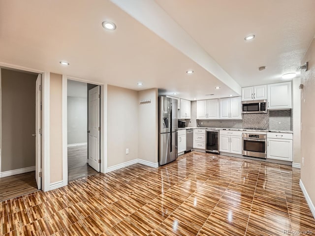 kitchen featuring white cabinets, wine cooler, backsplash, and appliances with stainless steel finishes