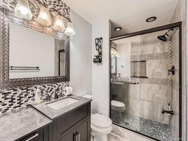 bathroom featuring vanity, toilet, walk in shower, and tasteful backsplash