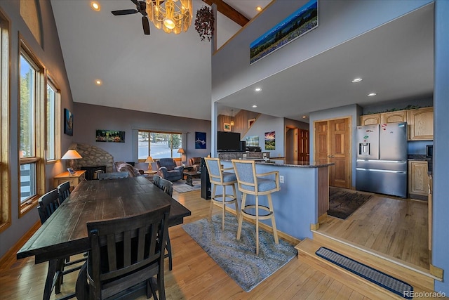 11222 Conifer Mountain Rd, Conifer, CO 80433 - kitchen featuring stainless steel refrigerator with ice dispenser, light wood-style flooring, ceiling fan, high vaulted ceiling, and a breakfast bar area