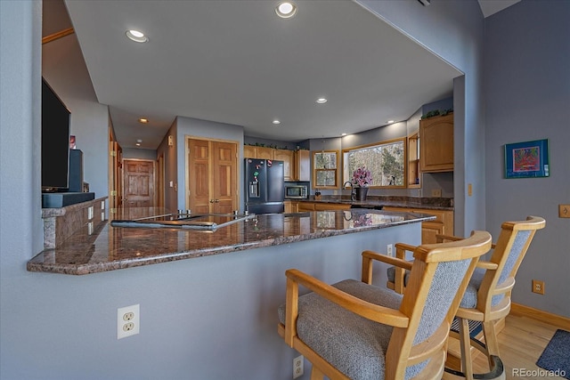 11222 Conifer Mountain Rd, Conifer, CO 80433 - kitchen featuring black appliances, a peninsula, dark stone counters, recessed lighting, and light wood-style floors