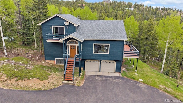11222 Conifer Mountain Rd, Conifer, CO 80433 - view of front of house featuring a balcony, stairway, asphalt driveway, an attached garage, and a forest view
