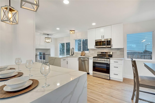 kitchen featuring sink, white cabinetry, hanging light fixtures, and appliances with stainless steel finishes