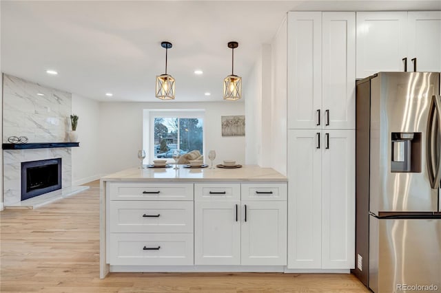 kitchen with hanging light fixtures, white cabinetry, a fireplace, light hardwood / wood-style floors, and stainless steel fridge with ice dispenser