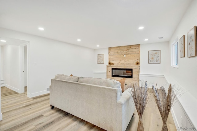 living room with a tiled fireplace and light hardwood / wood-style flooring