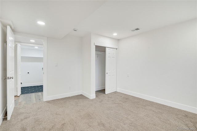 unfurnished bedroom featuring light carpet and a closet