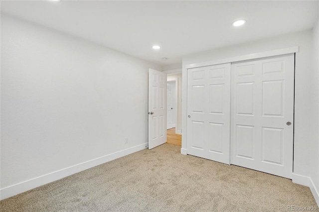 unfurnished bedroom with light carpet and a closet