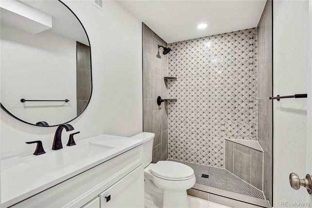 bathroom with vanity, toilet, and a tile shower