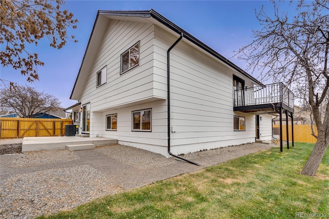 back of property with a balcony, central air condition unit, a yard, and a patio