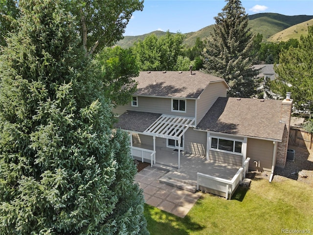 34 Honey Locust, Littleton, CO 80127 - rear view of house with a shingled roof, a deck with mountain view, and a chimney