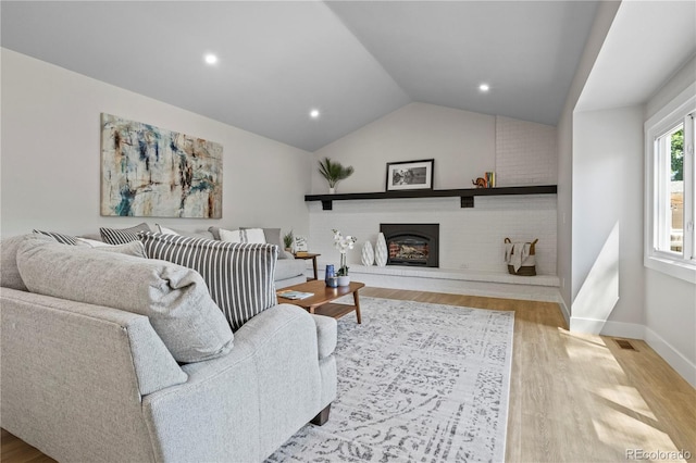 34 Honey Locust, Littleton, CO 80127 - living room with wood finished floors, vaulted ceiling, a brick fireplace, and recessed lighting
