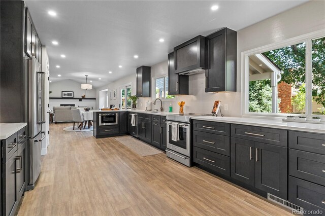 34 Honey Locust, Littleton, CO 80127 - kitchen with appliances with stainless steel finishes, light countertops, open floor plan, light wood-type flooring, and recessed lighting