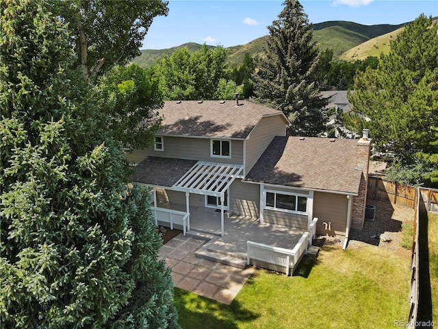 34 Honey Locust, Littleton, CO 80127 - back of house featuring a shingled roof, a fenced backyard, a deck with mountain view, and a chimney