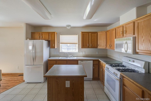 kitchen with white appliances, a sink, a kitchen island, and brown cabinets