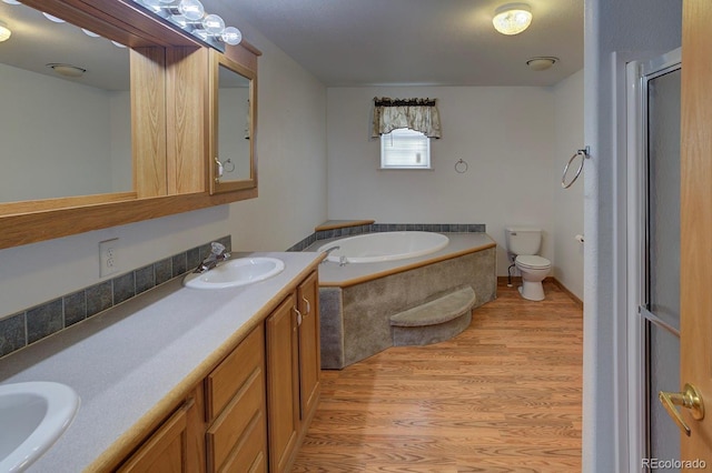 full bathroom featuring wood finished floors, double vanity, a garden tub, and a shower with door