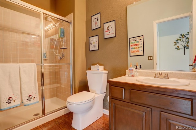 bathroom featuring hardwood / wood-style floors, vanity, toilet, and a shower with door