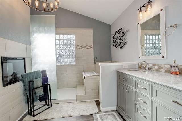 bathroom with vanity, tiled shower, a chandelier, and vaulted ceiling