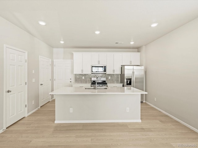 kitchen with white cabinets, appliances with stainless steel finishes, a center island with sink, and sink