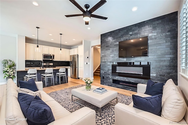 606 E Dry Creek Pl, Littleton, CO 80122 - living room featuring a ceiling fan, light wood-type flooring, recessed lighting, a fireplace, and stairway