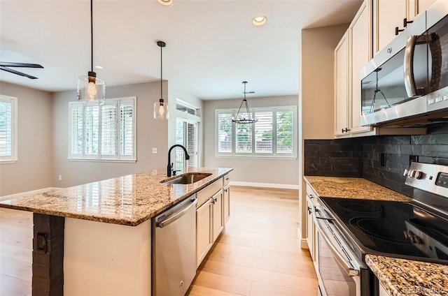 606 E Dry Creek Pl, Littleton, CO 80122 - kitchen featuring appliances with stainless steel finishes, ceiling fan, light stone countertops, decorative backsplash, and a center island with sink