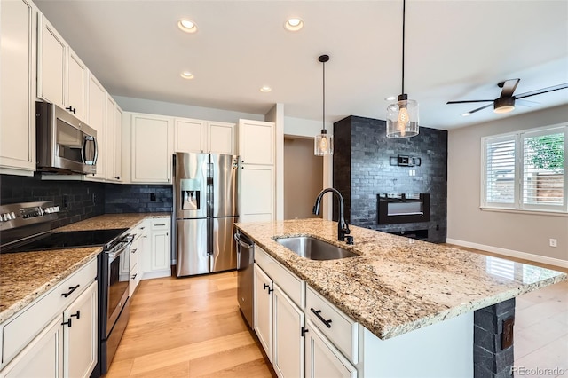 606 E Dry Creek Pl, Littleton, CO 80122 - kitchen featuring stainless steel appliances, tasteful backsplash, a center island with sink, a ceiling fan, and white cabinetry