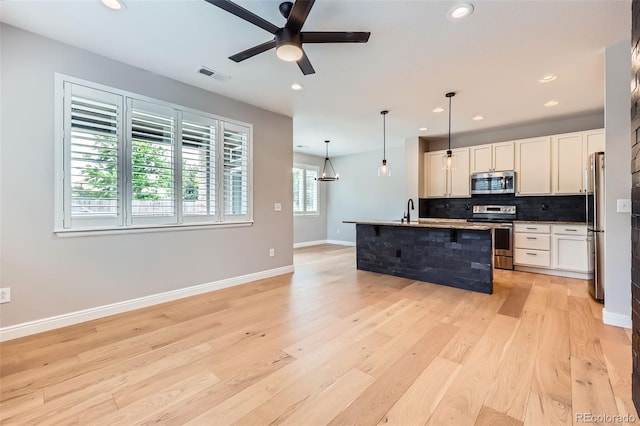 606 E Dry Creek Pl, Littleton, CO 80122 - kitchen featuring appliances with stainless steel finishes, light wood finished floors, ceiling fan, backsplash, and white cabinetry
