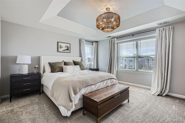 bedroom with light colored carpet, a raised ceiling, baseboards, and visible vents