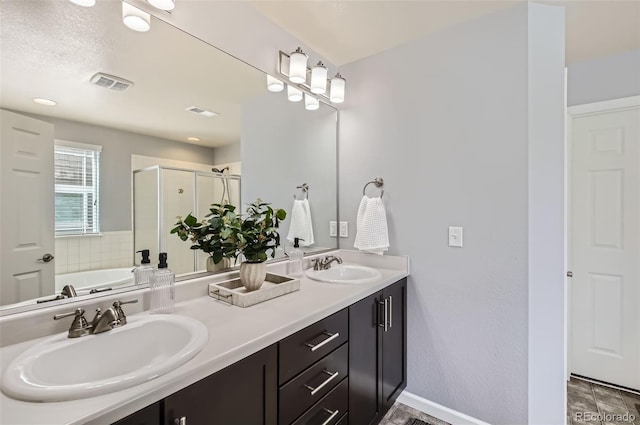 full bath featuring a sink, a shower stall, double vanity, and visible vents