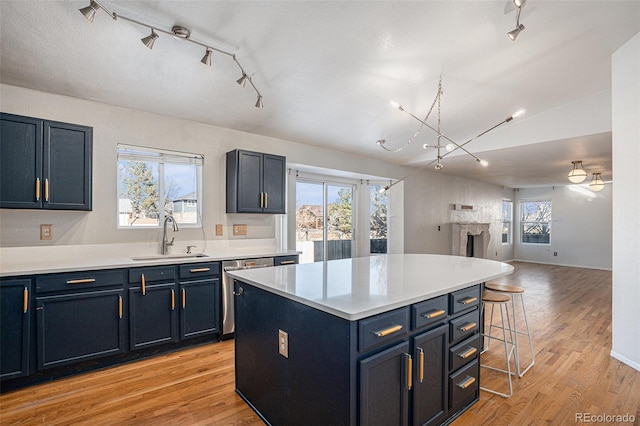 kitchen with stainless steel dishwasher, a breakfast bar, sink, blue cabinetry, and a center island