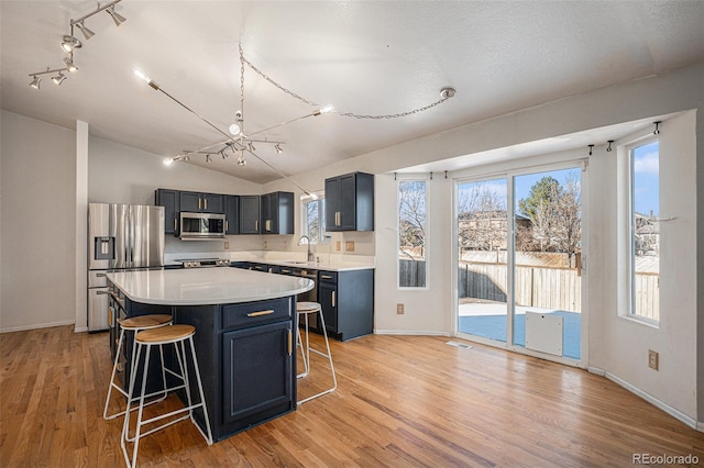 kitchen with a kitchen island, sink, appliances with stainless steel finishes, and light hardwood / wood-style flooring