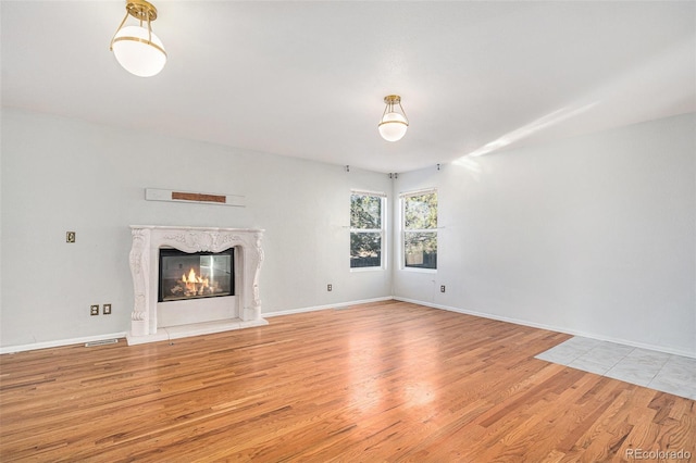 unfurnished living room featuring a high end fireplace and light wood-type flooring