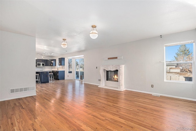 unfurnished living room with a high end fireplace and wood-type flooring