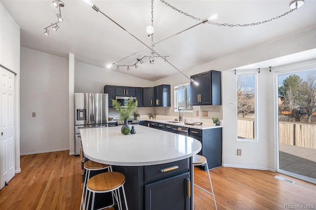 kitchen with visible vents, light wood finished floors, light countertops, appliances with stainless steel finishes, and a kitchen breakfast bar