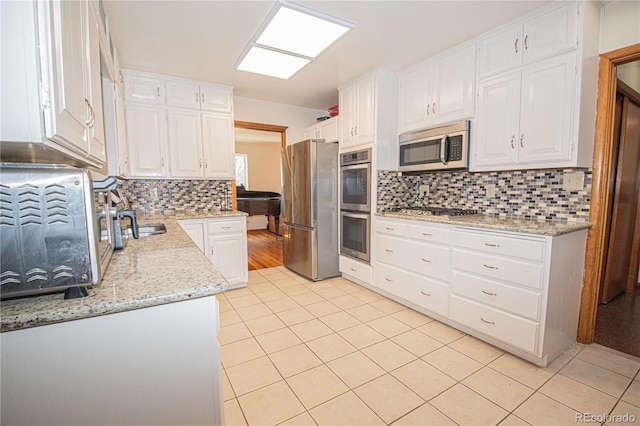 kitchen featuring light tile patterned floors, light stone counters, white cabinetry, decorative backsplash, and stainless steel appliances