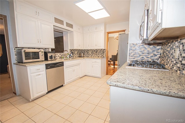 kitchen featuring a sink, white cabinetry, backsplash, appliances with stainless steel finishes, and light tile patterned flooring