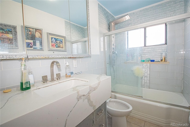 bathroom with toilet, tile walls, tile patterned flooring, bath / shower combo with glass door, and vanity