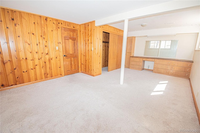 unfurnished bedroom featuring carpet, built in study area, and wood walls