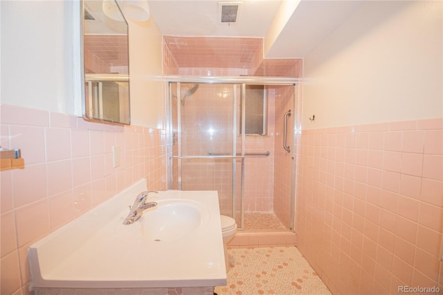bathroom with tile walls, visible vents, a shower stall, tile patterned floors, and vanity